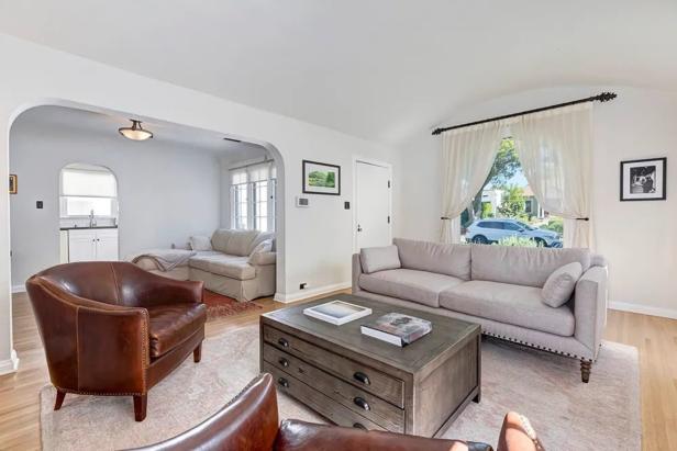 Ein Wohnzimmer mit hellen Wänden, einem grauen Sofa und zwei braunen Ledersesseln.