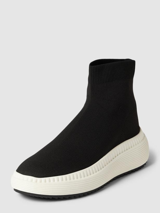 Ein schwarzer Stoffschuh mit einer dicken, weißen Sohle.