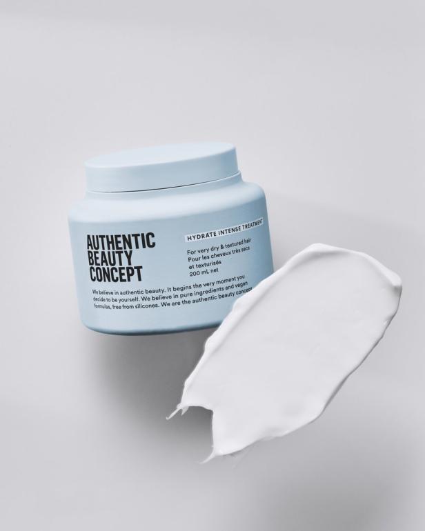 Ein Tiegel „Authentic Beauty Concept Hydrate Intense Treatment“ mit einem Klecks der weißen Creme daneben.