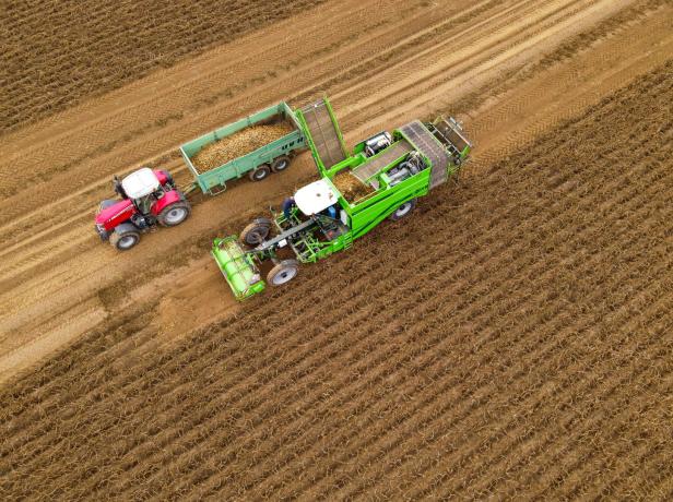 Ein Traktor und eine Erntemaschine arbeiten auf einem Feld.