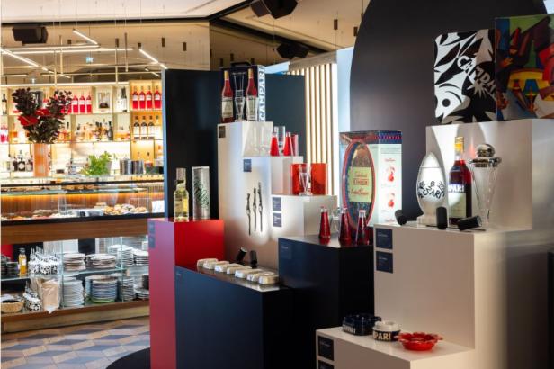 Eine Ausstellung von Campari-Flaschen, Gläsern und Werbeartikeln in einem Geschäft.