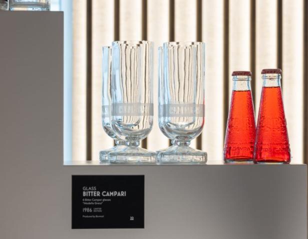 Campari-Gläser und -Flaschen stehen auf einem Regal.