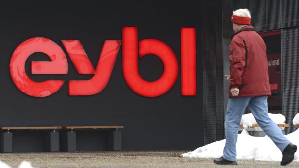 Ein Mann geht an einem Gebäude mit dem roten „eybl“-Logo vorbei.