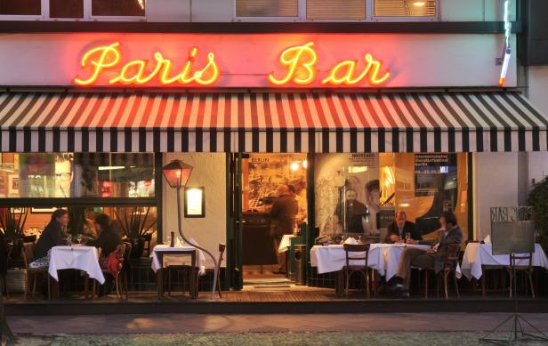Die „Paris Bar“ in Berlin mit Gästen an Tischen im Außenbereich.