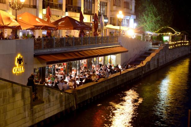 Das Restaurant „Grill Royal“ in Berlin bei Nacht, beleuchtet und mit Gästen besetzt.