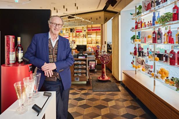 Ein Mann in einem Campari-Shop mit Regalen voller Flaschen und Gläsern.