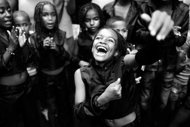 Eine Gruppe aufgeregter Kinder jubelt und lacht in Schwarzweiß.