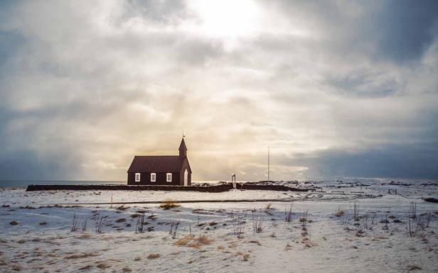 Die schwarze Kirche von Búðir in Island unter einem bewölkten Himmel.