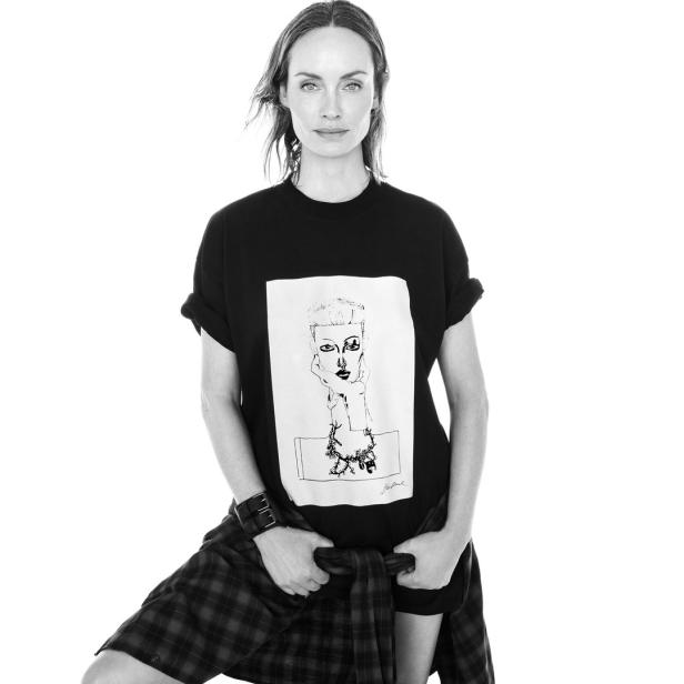Eine Frau in Schwarzweiß, die ein T-Shirt mit einer Zeichnung und einen karierten Rock trägt.