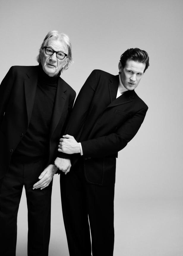 Der ältere Schauspieler John Hurt und Matt Smith posieren in Anzügen für ein Schwarzweißporträt.