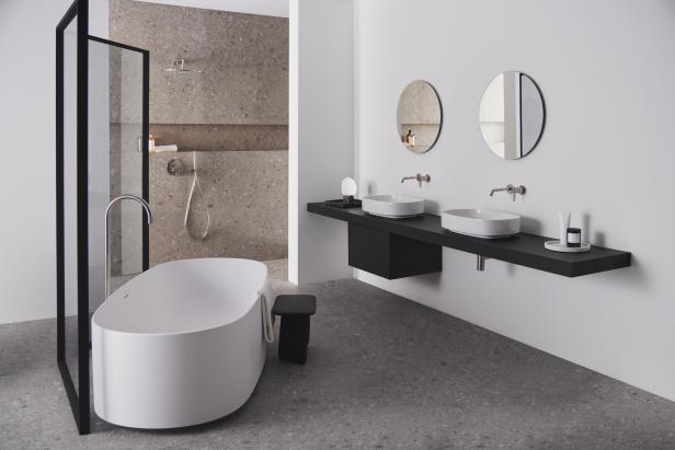 Ein modernes Badezimmer mit freistehender Badewanne und zwei Waschbecken mit runden Spiegeln.