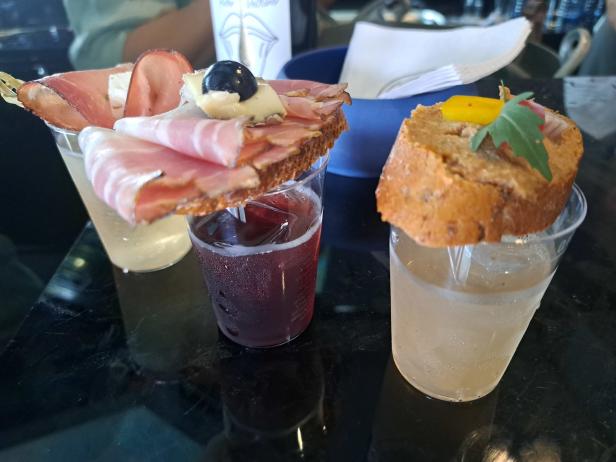 Drei Getränke mit Canapés stehen auf einem Tisch.