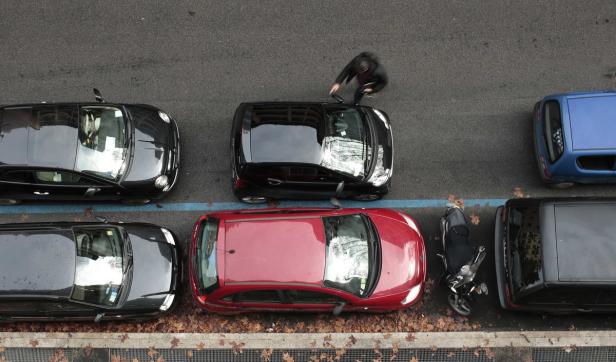 Eine Draufsicht auf geparkte Autos und ein Motorrad entlang einer Straße.