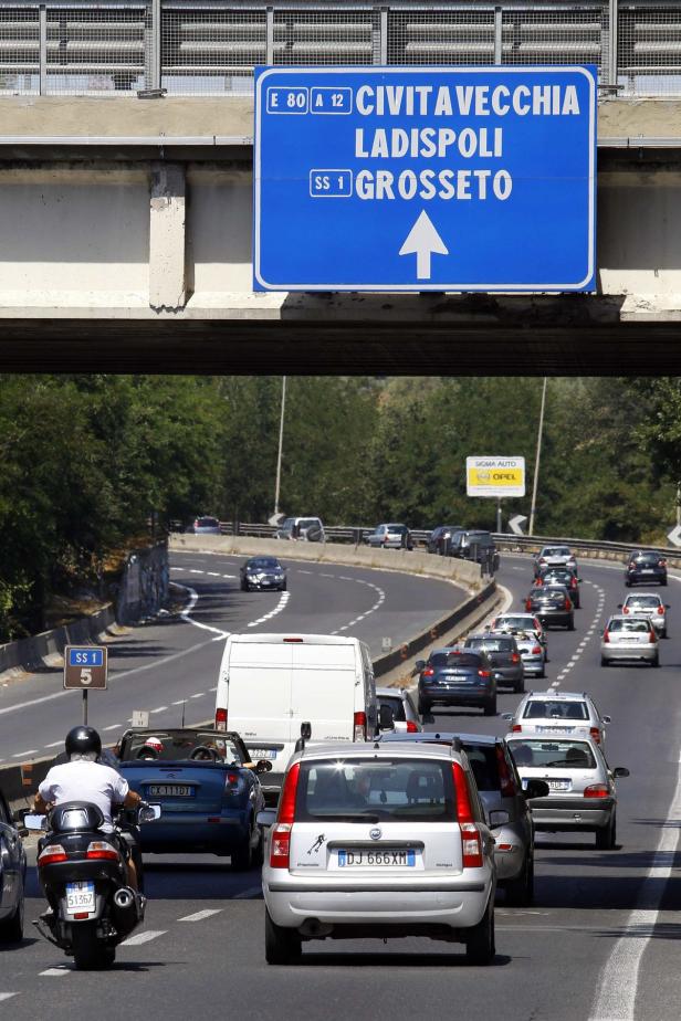 Verkehr auf einer Autobahn unter einem Schild nach Civitavecchia, Ladispoli und Grosseto.