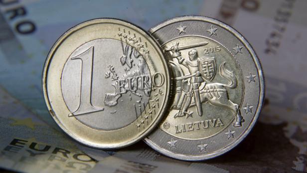 Eine 1-Euro-Münze und eine litauische 2-Euro-Gedenkmünze liegen auf einem Geldschein.