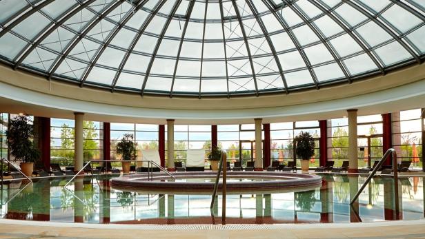 Ein Innenpool mit Liegestühlen unter einer Glaskuppel.