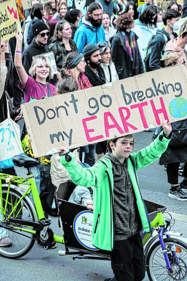 Ein Kind hält ein Schild mit der Aufschrift „Don't go breaking my EARTH“ bei einer Demonstration.