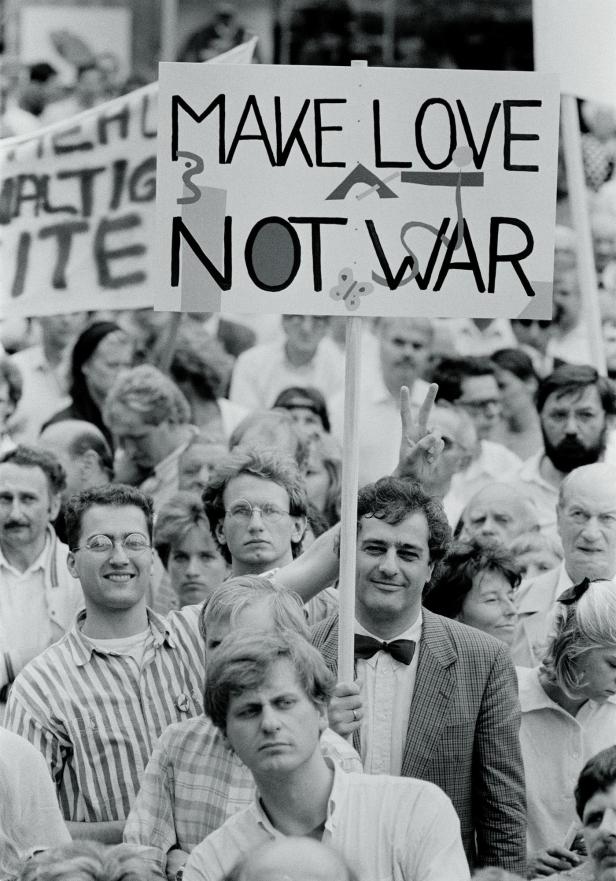 Eine Menschenmenge demonstriert mit einem Schild „Make Love Not War“.