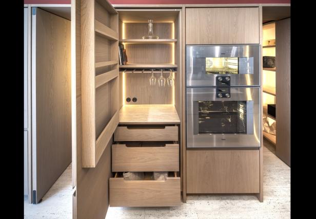 Ein Küchenschrank aus hellem Holz mit Regalen, Schubladen und einem eingebauten Ofen.