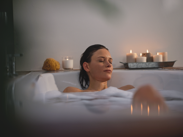 Eine Frau entspannt mit geschlossenen Augen in einer mit Schaum gefüllten Badewanne.