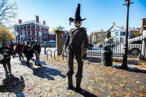 Eine Jack Skellington-Figur steht auf einem Bürgersteig mit Herbstlaub.
