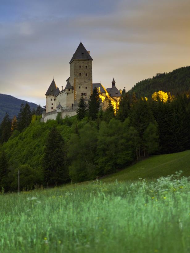 Burg Mauterndorf thront auf einem Hügel, umgeben von grünen Wiesen und Bäumen.