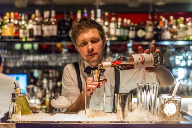 Ein Barkeeper mixt einen Drink mit Jachmann und Wermut.
