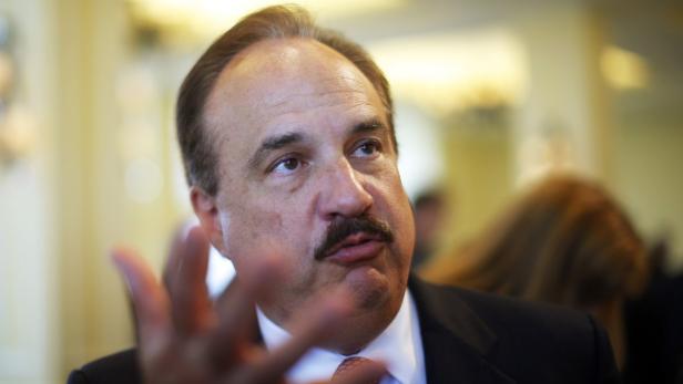 Ein Mann mit Schnurrbart gestikuliert während eines Gesprächs.