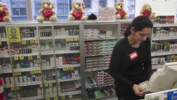 Eine Kassiererin steht hinter der Theke eines Tabakladens und zählt Geld.