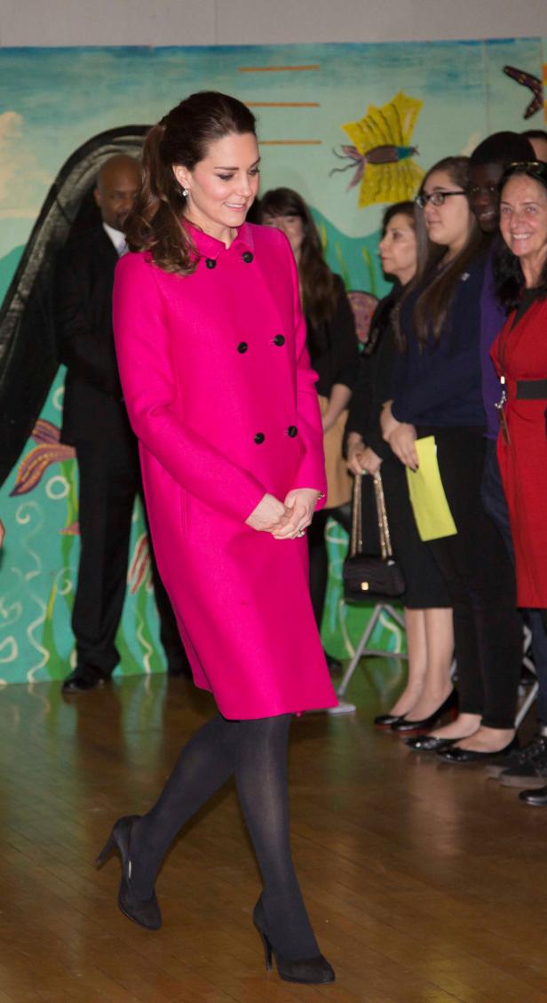 Kate Middleton in einem pinkfarbenen Mantel bei einem Besuch in einer Schule.
