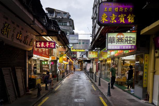 Eine belebte Gasse in Macau mit zahlreichen chinesischen Schriftzeichen auf den Schildern.