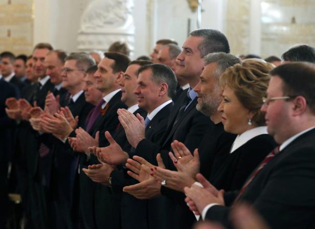 Eine Gruppe von Menschen in Anzügen applaudiert.