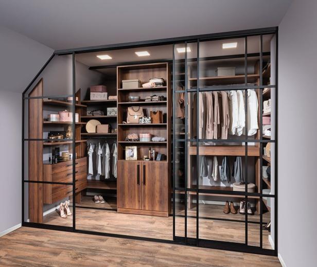 Ein begehbarer Kleiderschrank mit Holzregalen und schwarzem Metallrahmen.