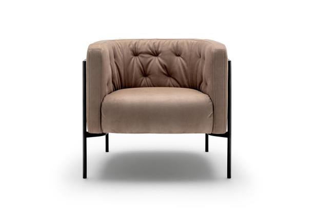 Ein beiger Sessel mit Knopfheftung und schwarzem Metallgestell vor weißem Hintergrund.