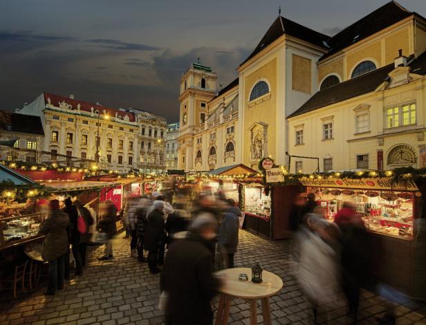 Ein belebter Weihnachtsmarkt in Wien mit Menschen und Verkaufsständen.