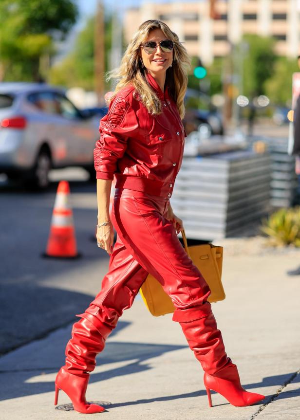 Heidi Klum trägt ein rotes Lederoutfit und eine gelbe Handtasche.