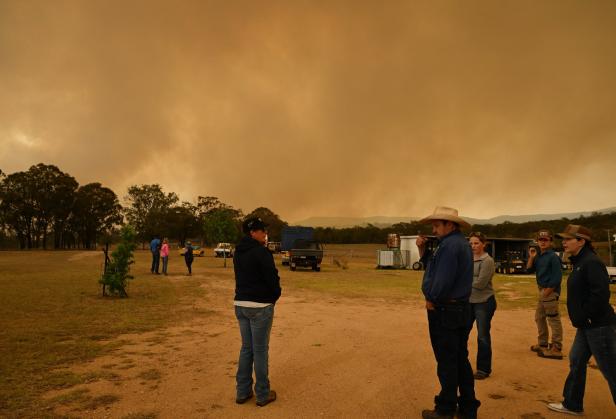 Eine Gruppe von Menschen steht auf einem Feld unter einem orangefarbenen Himmel.