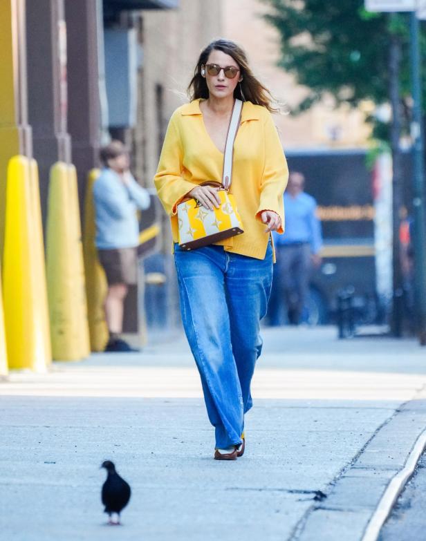 Blake Lively geht in Jeans und einem gelben Oberteil die Straße entlang.