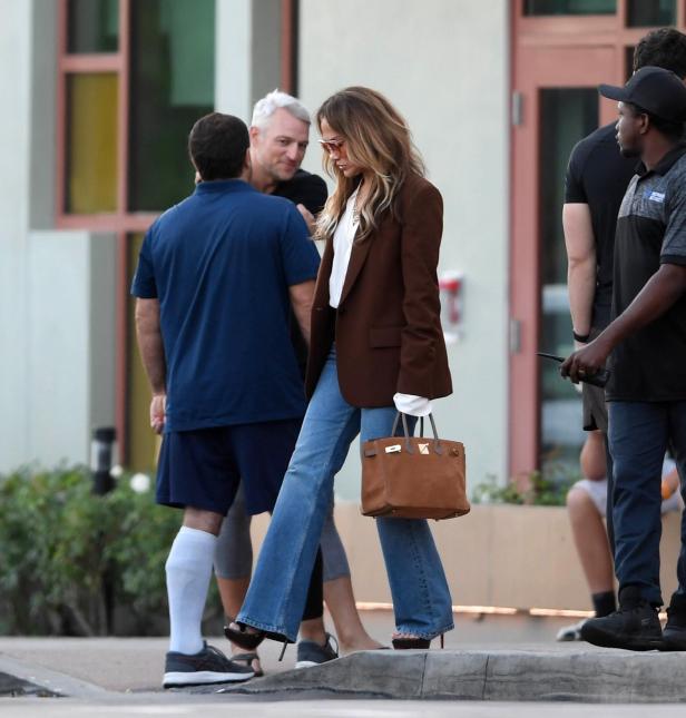 Jennifer Lopez trägt Jeans, einen Blazer und eine Handtasche.