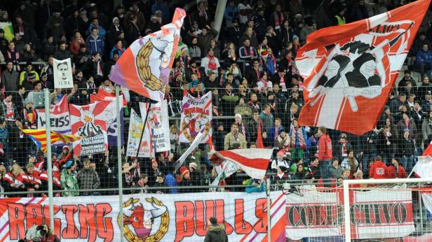 Zuschauer mit Fahnen und Bannern bei einem Fußballspiel.