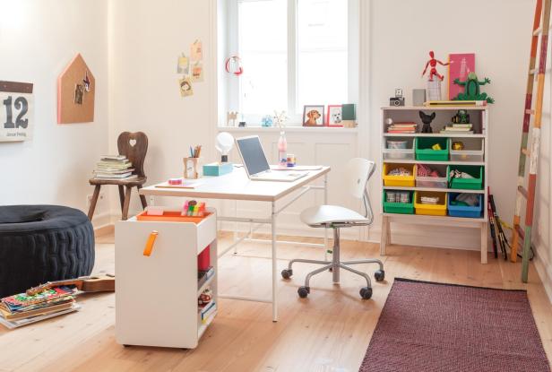 Ein Kinderzimmer mit Schreibtisch, Stuhl und einem Regal voller Spielsachen.