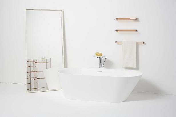 Ein freistehende Badewanne in einem Badezimmer mit Spiegel und Regalen.