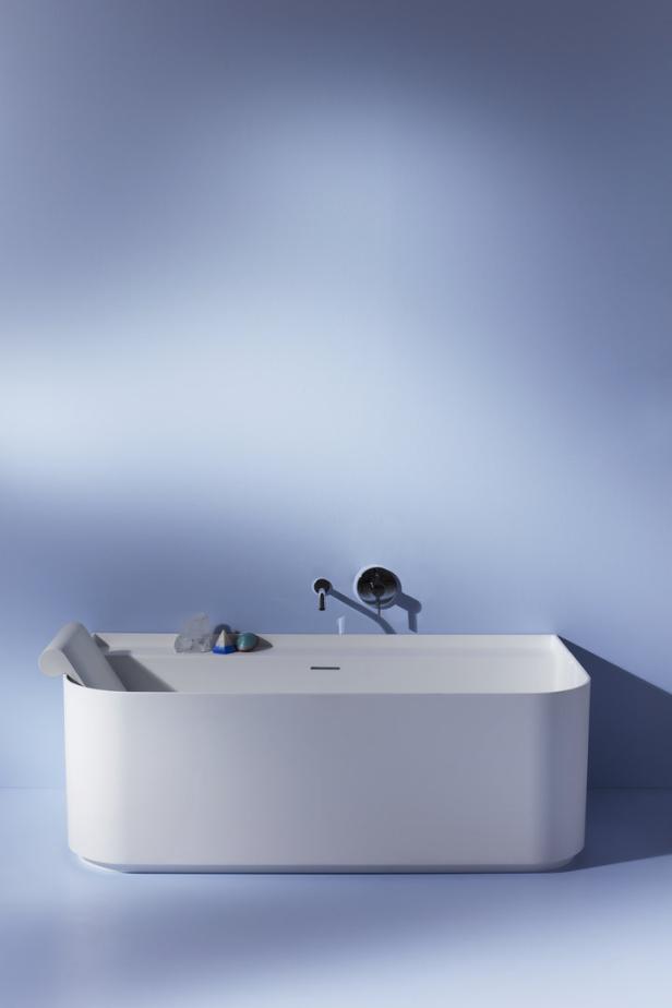 Eine moderne, rechteckige Badewanne vor einer hellblauen Wand.