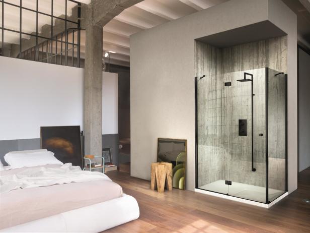 Ein Schlafzimmer mit Holzboden und einer begehbaren Dusche mit Glaswänden.