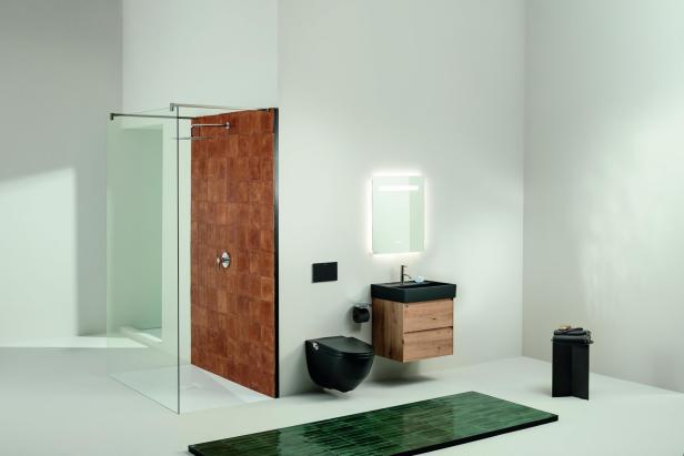 Ein modernes Badezimmer mit Dusche, Waschbecken, Toilette und grüner Badematte.