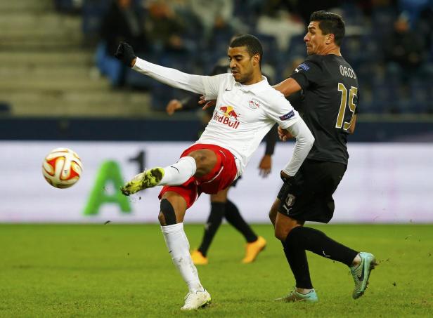 Ein Fußballspieler von Red Bull schießt den Ball, während ein Gegenspieler ihn beobachtet.
