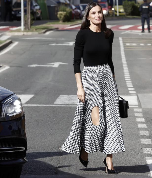 Königin Letizia überquert in einem schwarzen Oberteil und einem Rock mit Hahnentrittmuster eine Straße.