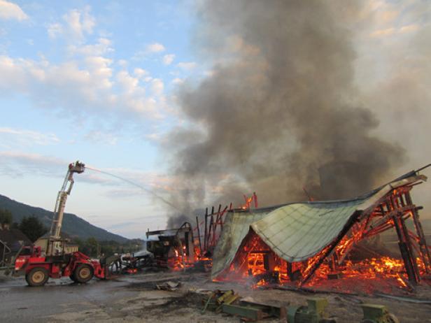 Ein Feuerwehrmann löscht ein brennendes Gebäude mit einem Wasserwerfer.