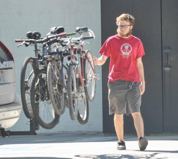 Ein Mann mit Brille steht neben einem Fahrradträger mit drei Fahrrädern.