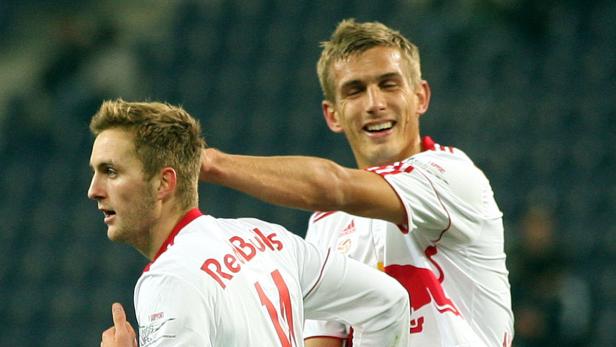 Zwei Fußballspieler von Red Bull jubeln auf dem Spielfeld.